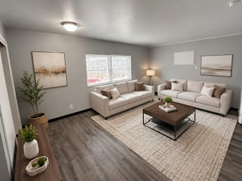 A living room with a white couch, a coffee table, and a plant.